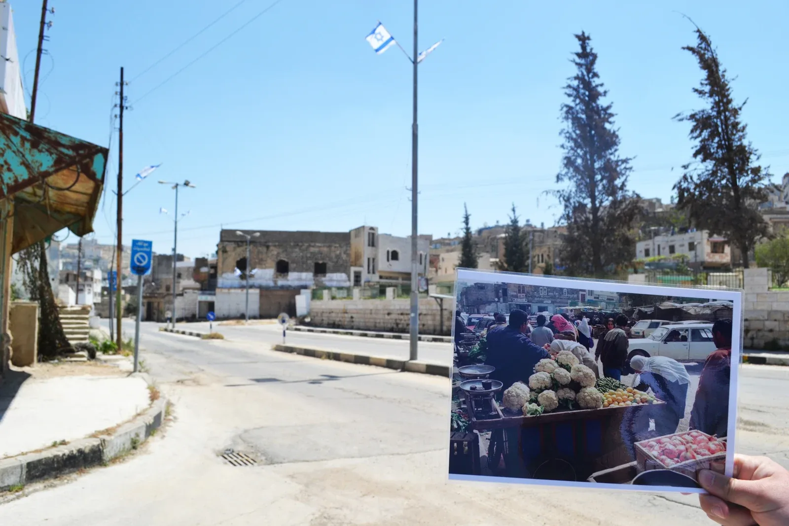 Shuhada Street di Hebron dalam foto arkib 17 Mei 2012, dengan foto lama pasar dipegang di hadapan kamera. Foto Eoghan Rice/Tr&oacute;caire